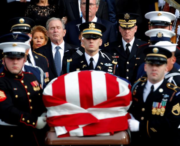 Ex-President George W. Bush follows a military honour guard as they carry the casket of his...