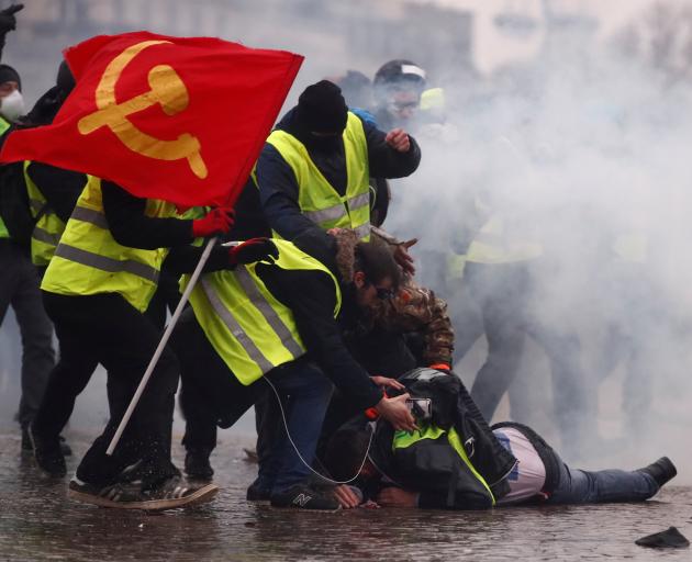 Protesters wearing yellow vests help a person injured by a water cannon during a demonstration by...