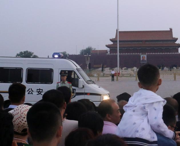 A paramilitary police officer stands guard as people wait for the flag-raising ceremony held at...