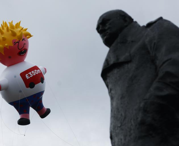 A giant inflatable blimp depicting Boris Johnson is flown near a statue of former British Prime...