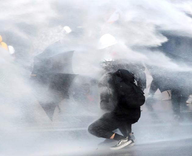 Anti-government protesters are sprayed with water cannon during a demonstration near Central...