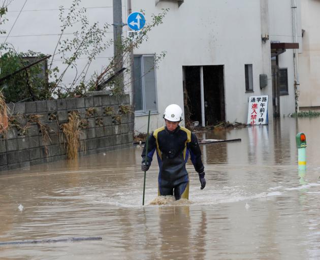 A rescue worker wades in water in the aftermath of Typhoon Hagibis, which caused severe floods,...
