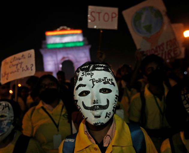 A boy wears a mask attends a protest demanding government to take immediate steps to control air...