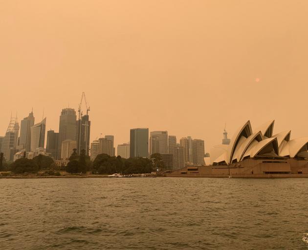 The haze from bushfires obscures the sun setting above the Sydney Opera House in Sydney. Photo:...