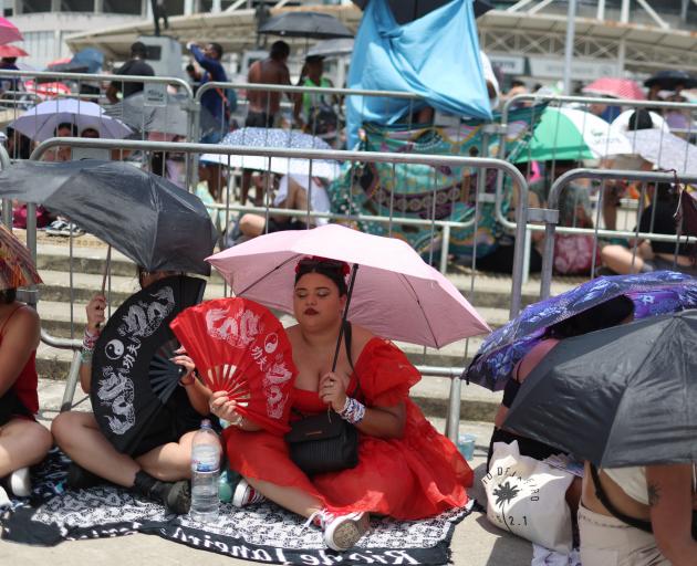 Fans waiting to get in to the show try and keep cool during the hot day in Rio de Janeiro. Photo:...