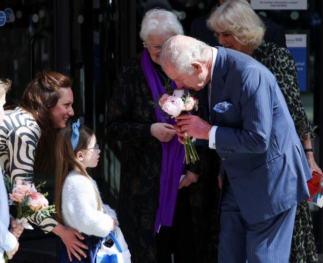 King Charles receives flowers from a young cancer patient. He was accompanied by Queen Camilla ...