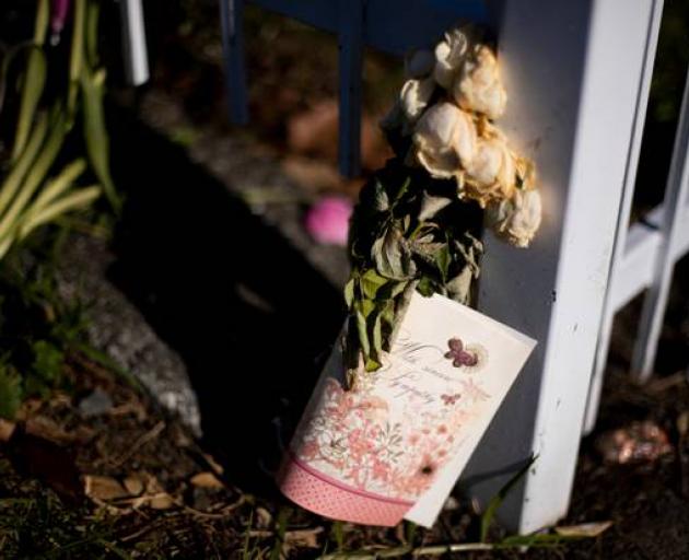 Roses left for Angela at the gate outside the entry to her flat, where police were stationed for a week after her death. Photo: Dean Purcell