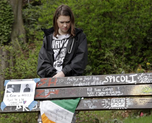 Grace Dubec, of Indianapolis., wears a Nirvana T-shirt as she looks over a park bench covered...