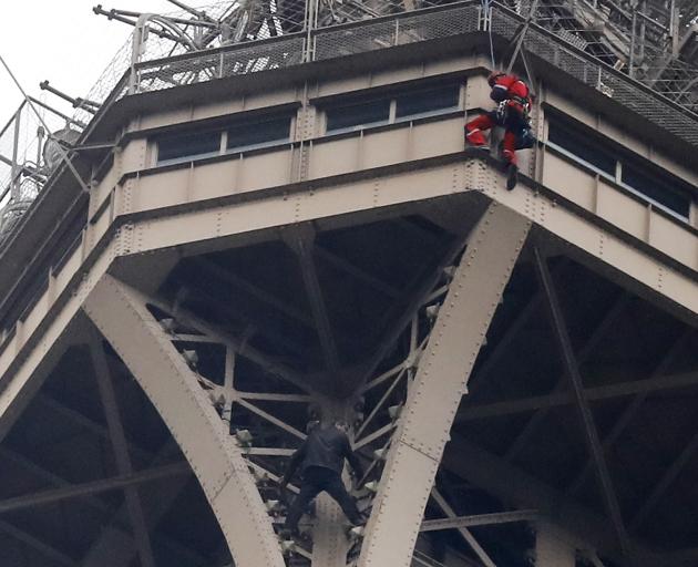 A rescue worker (above in red) descends to the man in black. Photo: AP