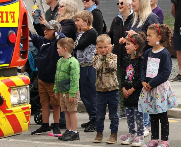 Young spectators cover their ears as the fire sirens on the vintage fire engine driven by the...