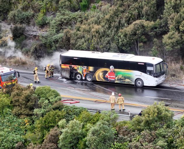 Fire fighters battle a blaze on a passenger bus on Dunedin's northern motorway. Photo: Stephen...