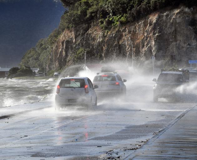 Waves from Otago Harbour are blown across the Portobello Road causeway. Photo: Stephen Jaquiery