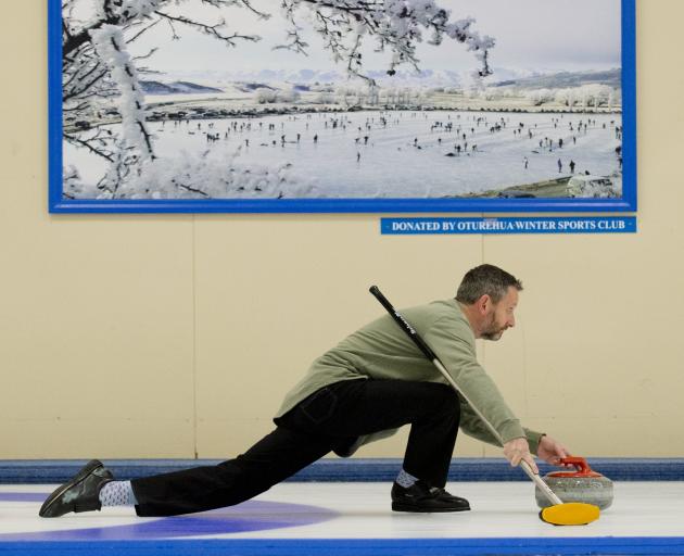 Kenny Thomson glides past a photograph of the 2001 Bonspiel at Idaburn during the national...