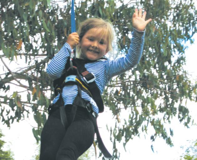 Eliza Isobell Bryant (5), of Te Anau, has time for a wave as she enjoys a ride on the flying fox....