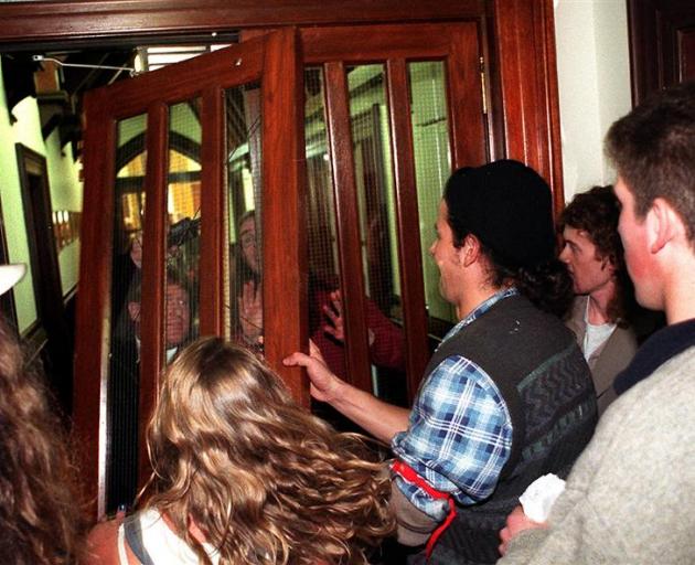 Protestors break down a door in the University of Otago Registry as they disrupt a University Council meeting in September 1997. The meeting was discussing cuts to the University's European languages and Classics departments.