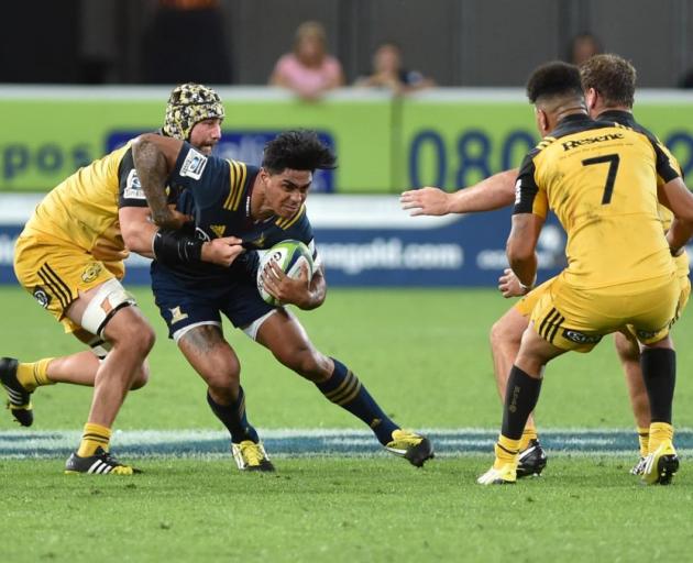 Highlanders centre Malakai Fekitoa is tackled by Hurricanes lock Blade Thomson  at Forsyth Barr Stadium on Saturday night. Hurricanes flanker Ardie Savea  (No7) and Reg Goodes (obscured) are also on the scene. Photo by Gregor Richardson. 