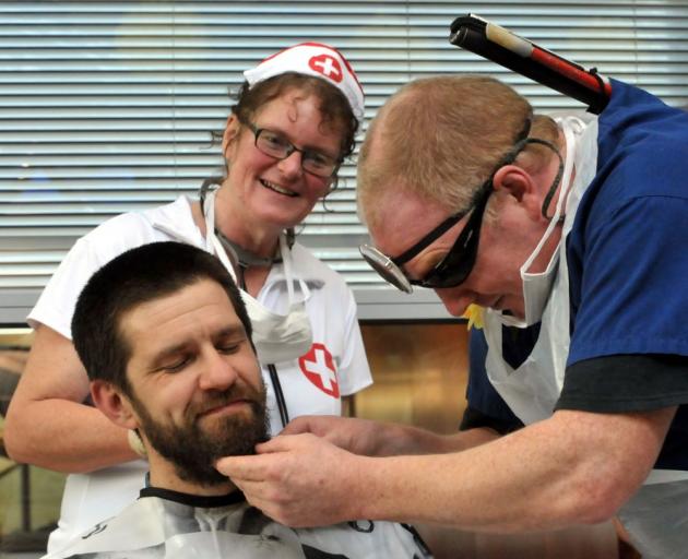 David Steer gets his head shaved yesterday by colleague Simon Fogarty, while Monica Barkman watches proceedings. Photo by Gregor Richardson