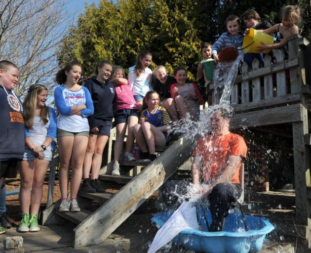 Outram School principal Jeremy Marshall gets icy water poured over him yesterday to fundraise for CanTeen. Photo by Gregor Richardson. 