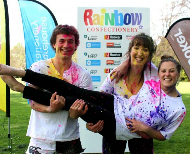 Logan Searle (18, left) and Mikaela Young (18), hold  Alice Kingan (17), all of Oamaru, after testing some of the colours which will be thrown at participants of the 2014 Rainbow Run
