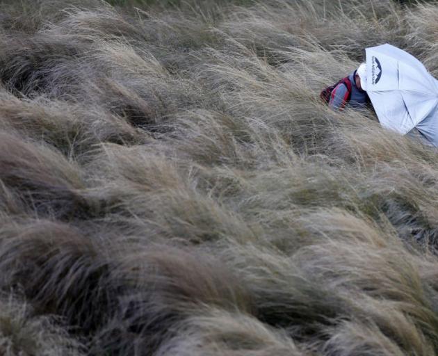 A spectator takes shelter at The Hills course this morning. PHOTO: PHOTOSPORT