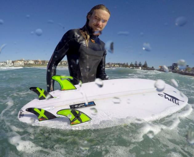 Arlen Macpherson checks the electronic shark repellent device he had installed in his board at Sydney's Bondi Beach. Photo: Reuters