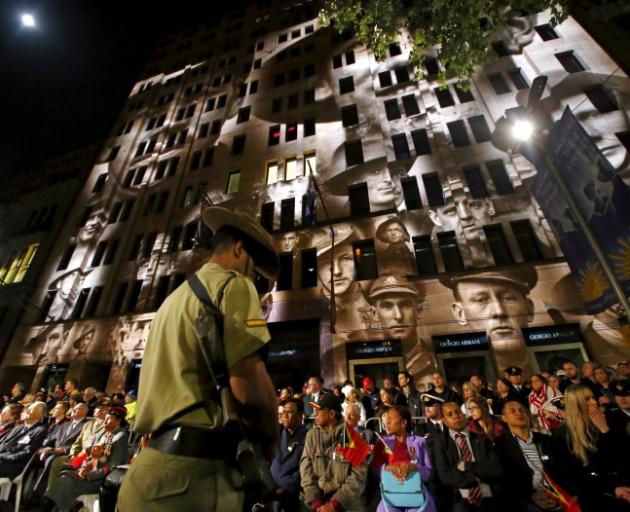 The faces of soldiers were projected onto a building during commemorations in Sydney this morning. Photo: Reuters