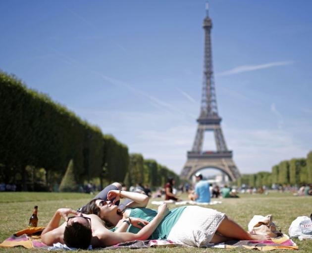 Tourists relax on the Champ de Mars in front of the Eiffel Tower in Paris earlier this month. Photo: Reuters