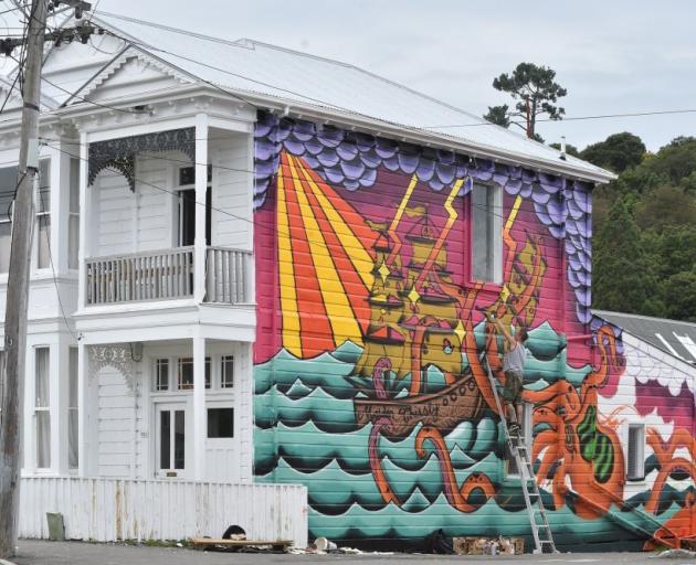 Street artist  Jack Pillans works on the mural yesterday. Photo: Peter McIntosh