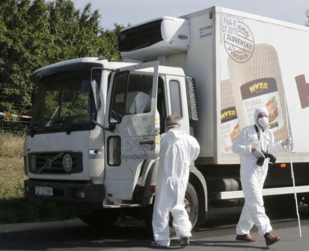 Forensic police officers inspect a parked truck in which up to 50 migrants were found dead, on a motorway near Parndorf, 
