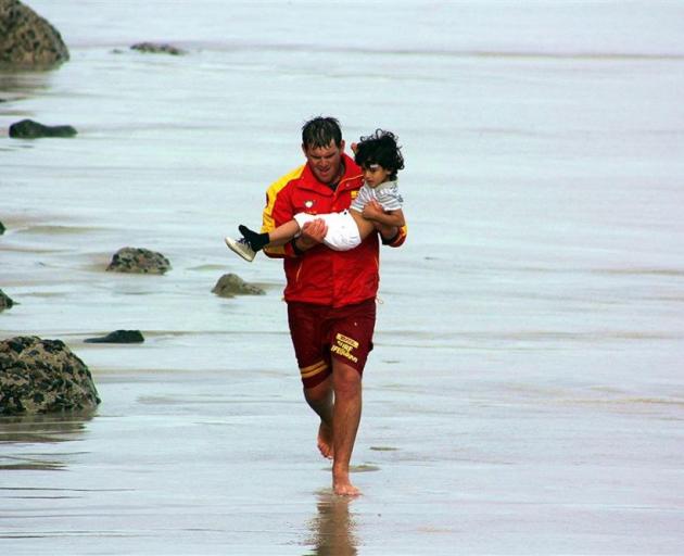 St Clair Surf Life Saving Club head guard Cam Burrow (20) rescues a 5-year-old boy on St Clair Beach on Saturday evening.  Photo by Christine Donegan