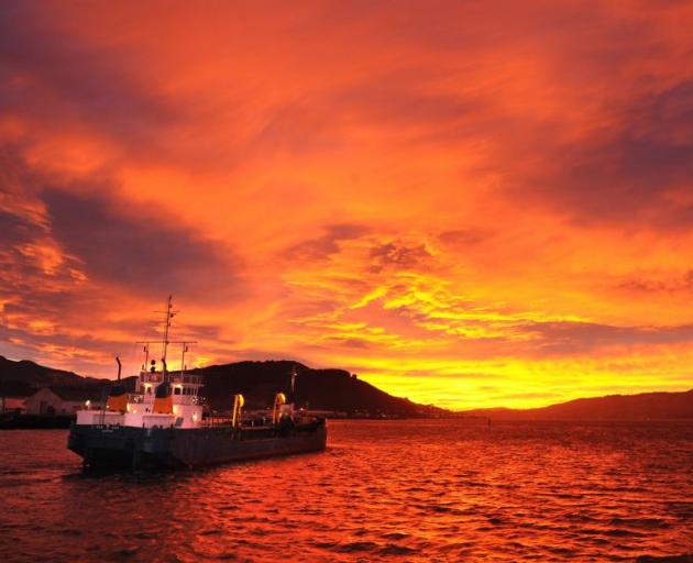 The dredge New Era sails into a red dawn on Otago Harbour. Photo: Stephen Jaquiery