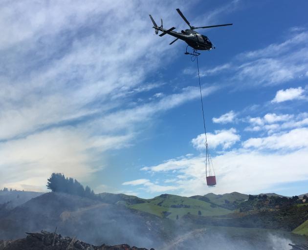 A helicopter with a monsoon bucket fights the fire at Bucklands Crossing. Photo: Stephen Jaquiery