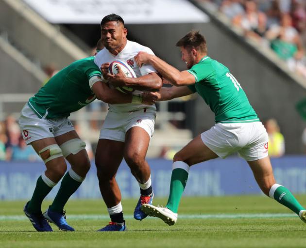 English midfield back Manu Tuilagi is tackled by Josh van der Flier (left) and Ross Byrne, of...