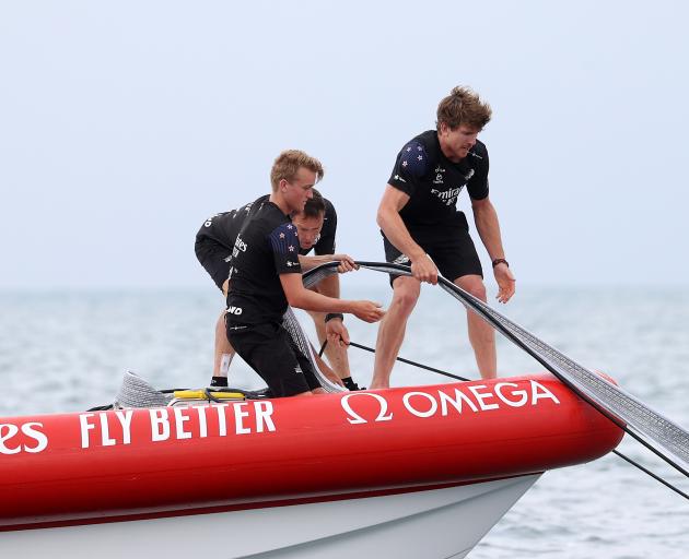 Team New Zealand skipper Peter Burling (right) helps retrieve a sail from the stricken American...
