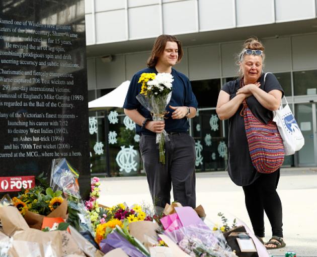 Fans lay floral tributes at the base of the Shane Warne statue outside the Melbourne Cricket...