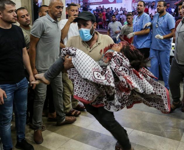 A man rushes a young girl through Nasser Medical Hospital following an air raid in Khan Yunis,...