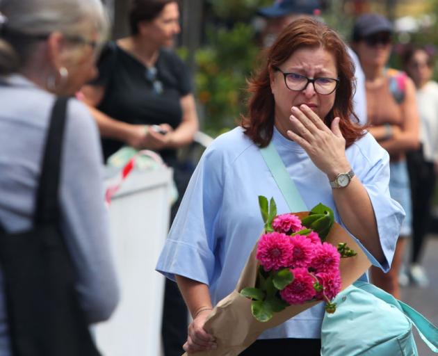 A woman prepares to lay flowers at  Oxford Street Mall on Sunday near the site of the stabbings,...