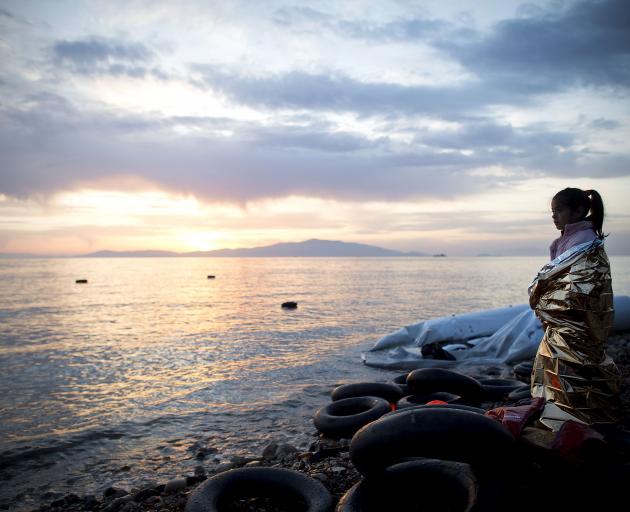 A Syrian girl looks on during sunrise, having crossed the sea from Turkey to Lesbos, Greece, in...