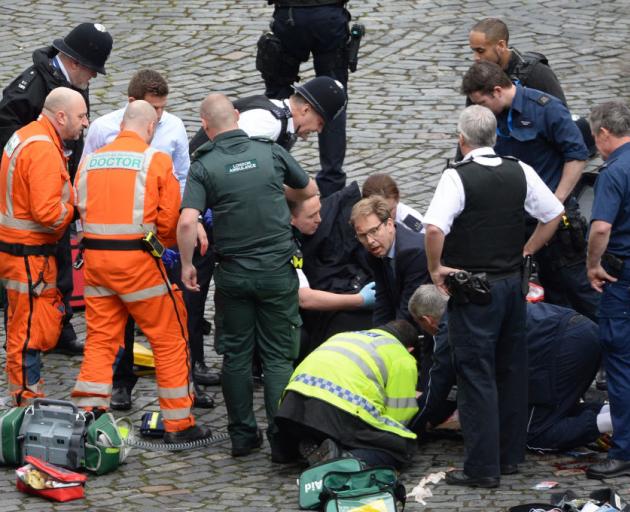 MP Tobias Ellwood (centre) helps emergency services attend to the shot officer. Photo: Getty Images 