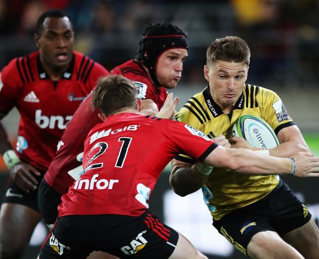 Beauden Barrett charges forward into a Crusaders tackle last night in his 100th match for the...