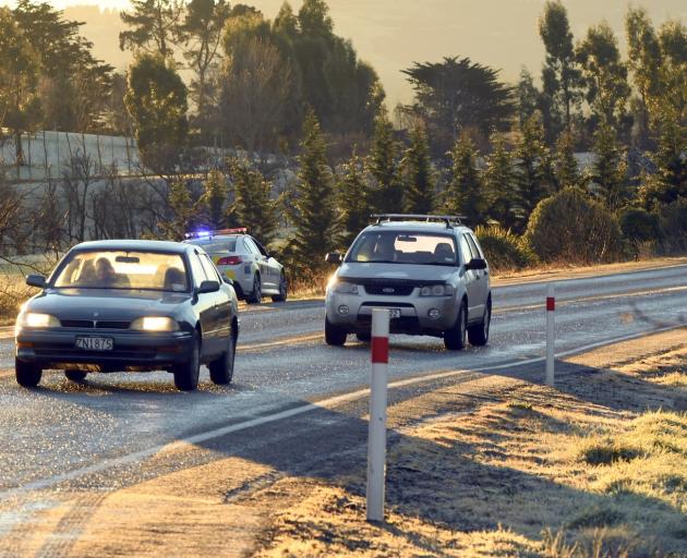 A police car slows traffic on State Highway 1 near East Taieri with black ice affecting many...
