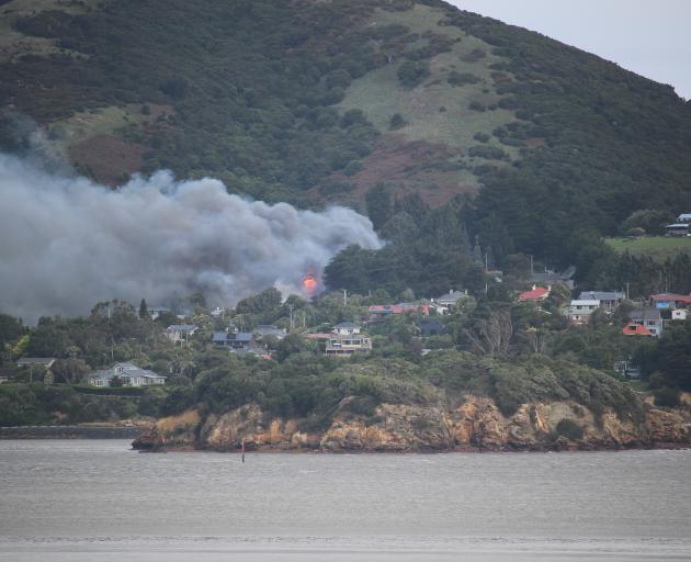 Smoke and flames can be seen pouring from the Beaconsfield Rd house from Port Chalmers. Photo:...