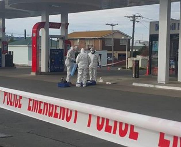 Police inspect the forecourt of the service station on Sunday. Photo: George Block 