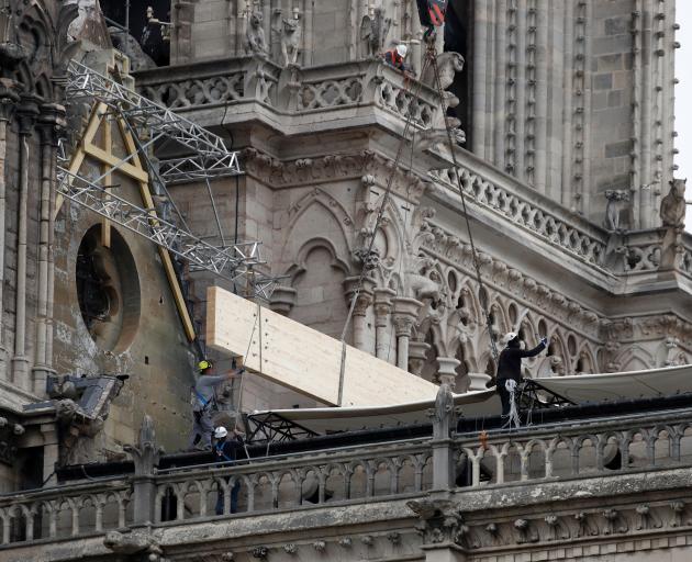 Workers install temporary tarpaulins to protect a fragile Notre-Dame Cathedral. Photo: Reuters 