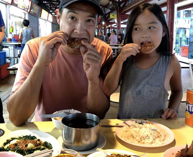 David Pierson eating fried chicken wings with his daughter, Ella, at Toa Payoh Lorong Food Centre.