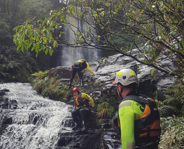 Members of a water rescue team abseil and search for Stephen Lowe at the McLean Falls in the...