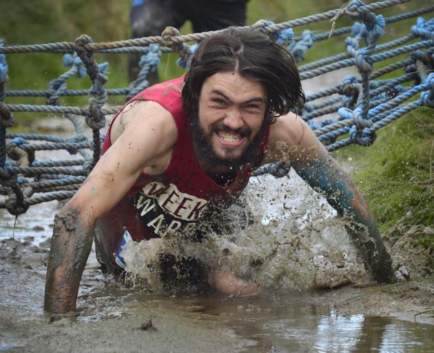 Mud, Sweat and Tears men’s 10km winner Jonah Smith, of Dunedin, crawls through a muddy ditch....