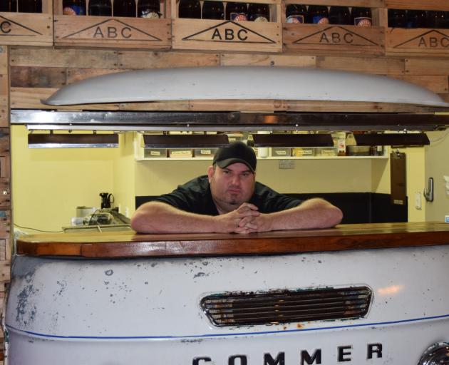 Fifty Gorillas Grill & Venue owner Ian Lindsay relaxes on a food serving counter made from a...