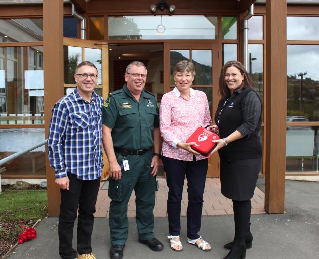 St John Coastal Otago territory manager Doug Third (second from left) hands over the donated AED...