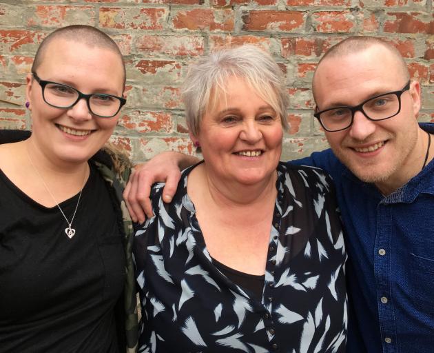 Maggie Garden (centre) is hugged by her children Amy and Chris Millar, who had their heads shaved...